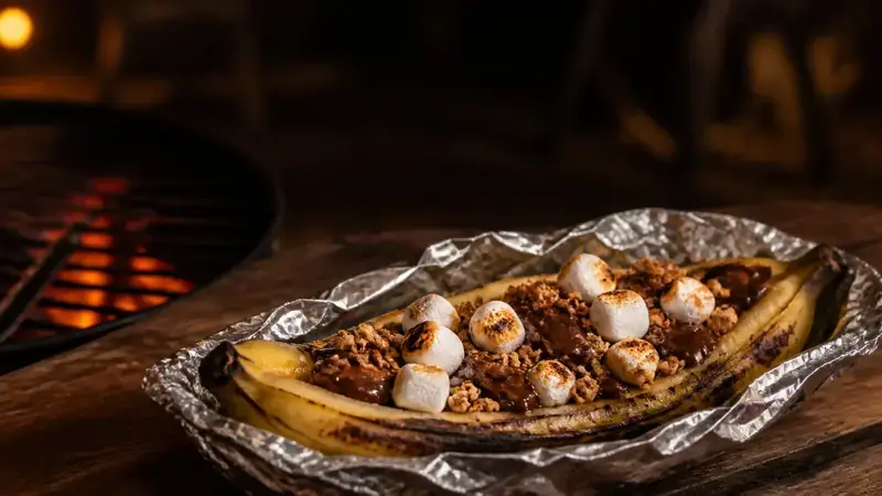 Gegrilde banaan uit de barbecue met gesmolten chocolade, geroosterde marshmallows en granencrunch.